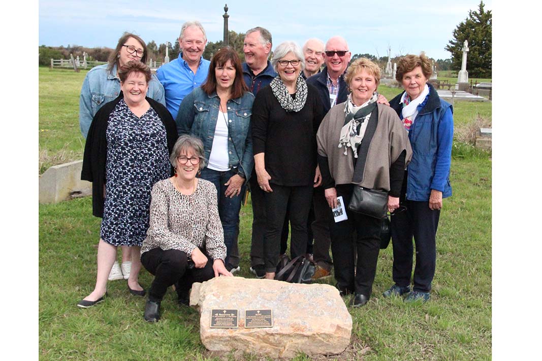 Judith McAninly ( kneeling) the secretary of the Greenmount Cemetery Committee and members of the Harkin family , with a rock bearing new plaques for those buried within the cemetery in unmarked graves.