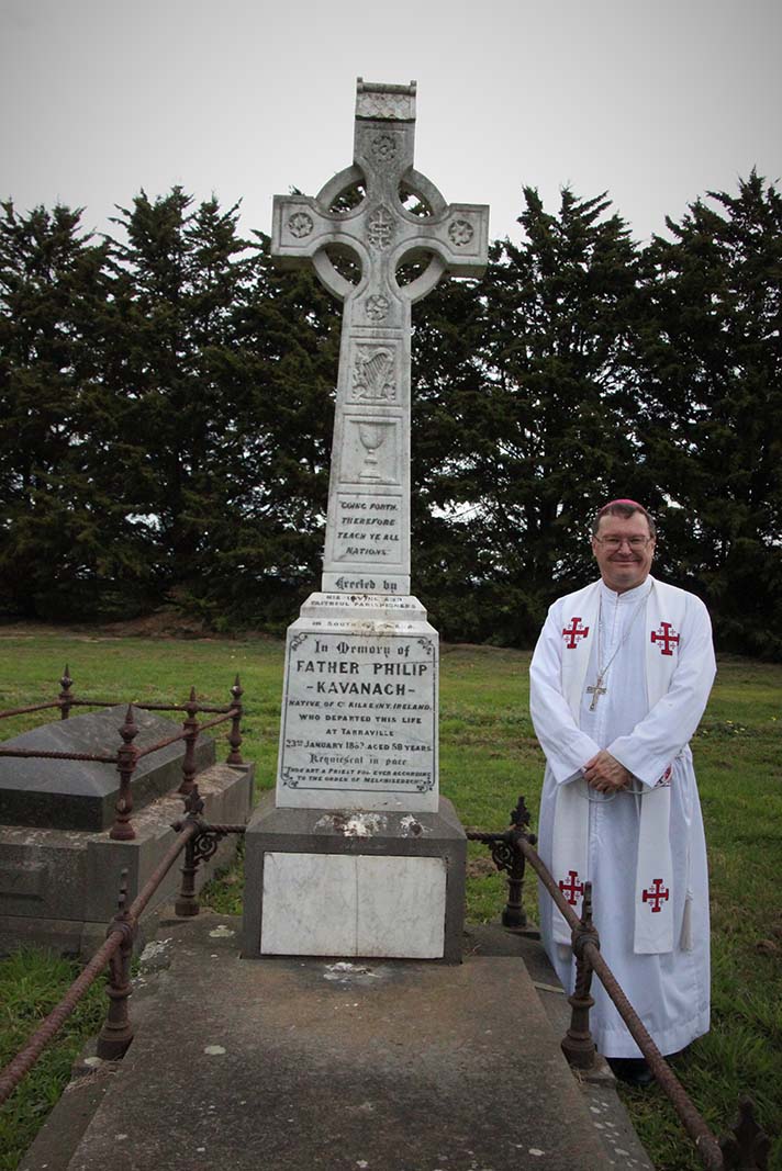 Bishop Pat stands beside the grave of Fr Phillip Kavanagh, the first priest to die and be buried within Gippsland.