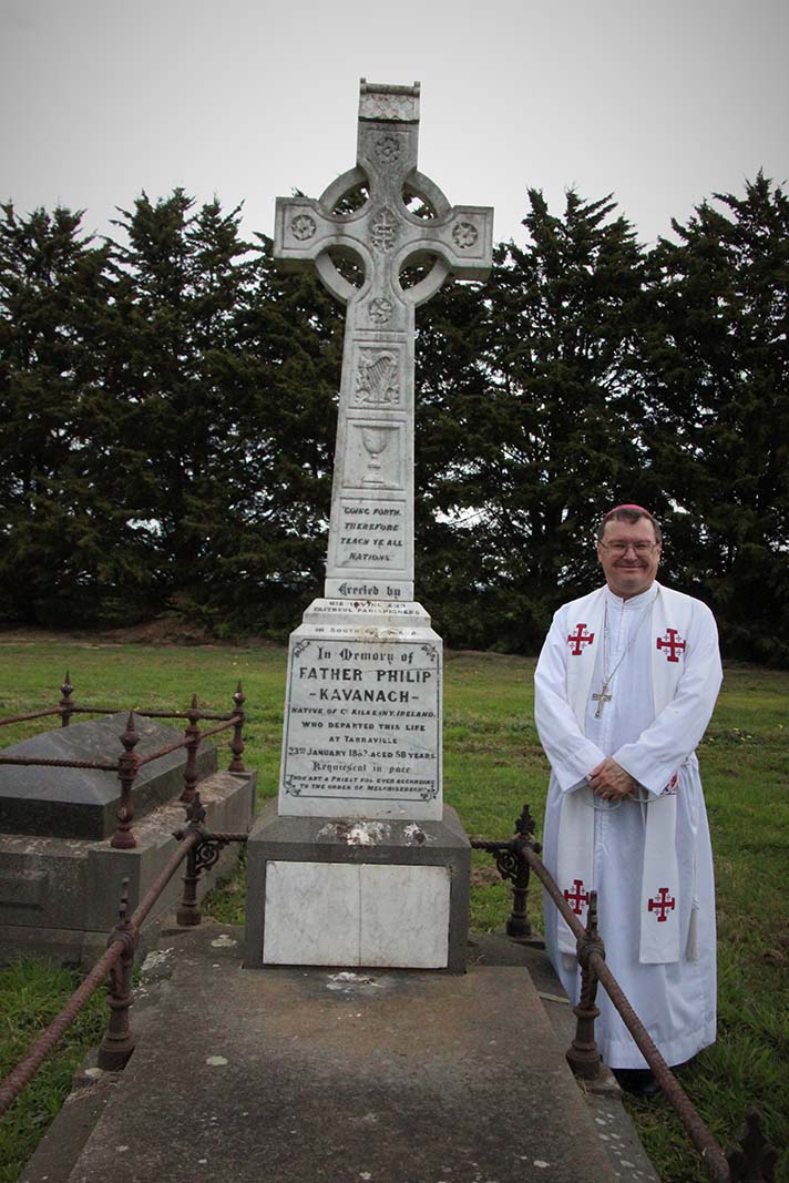 Bishop Pat stands beside the grave of Fr Phillip Kavanagh, the first priest to die and be buried within Gippsland.